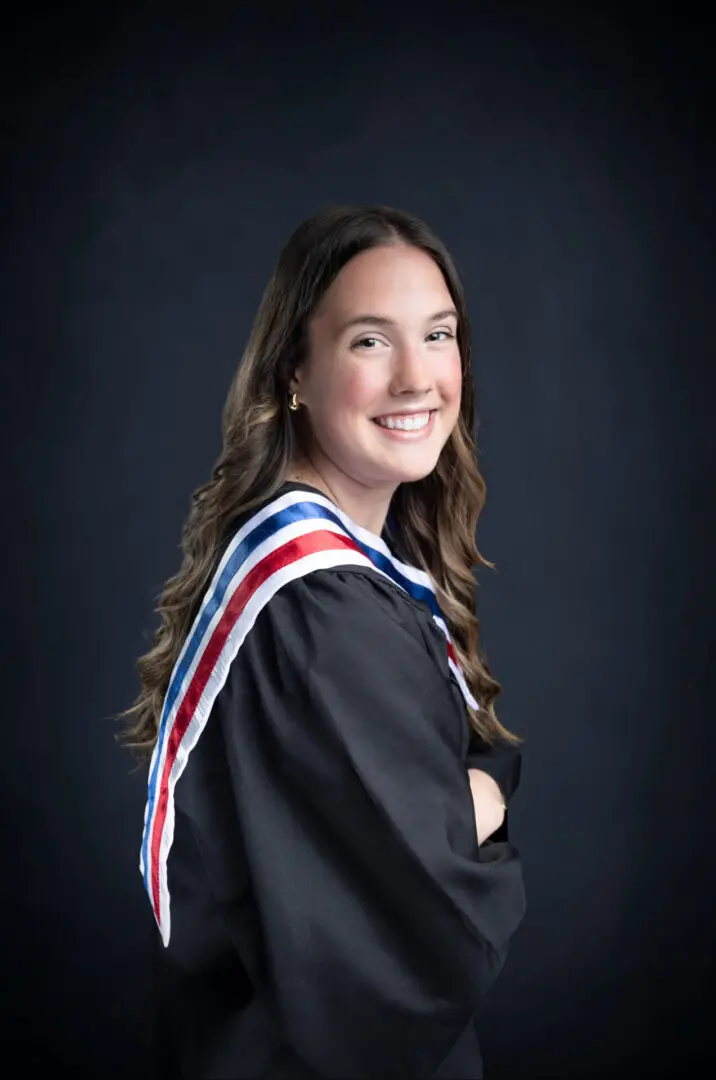 A woman in graduation gown smiling for the camera.