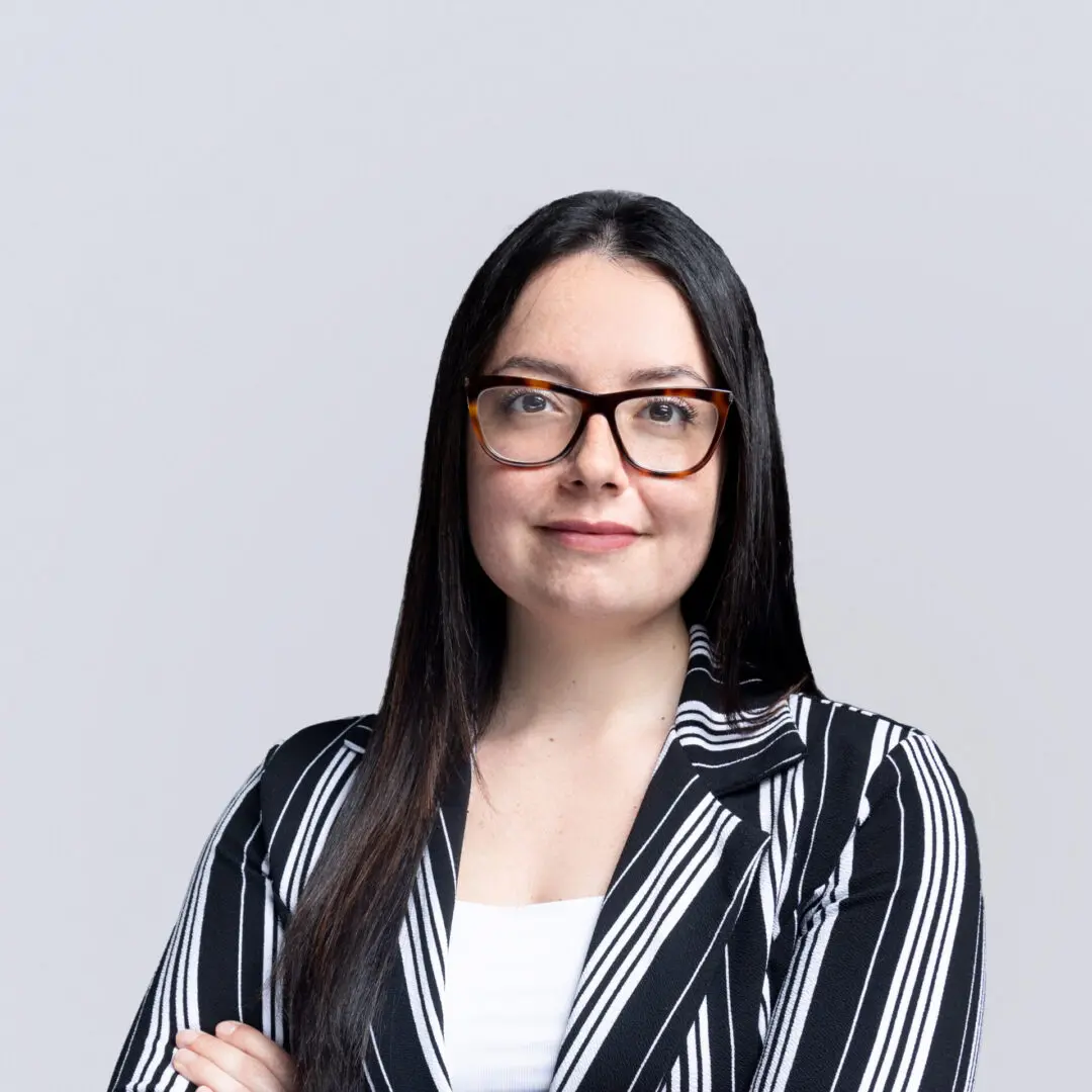 A woman with glasses and black hair wearing a striped jacket.