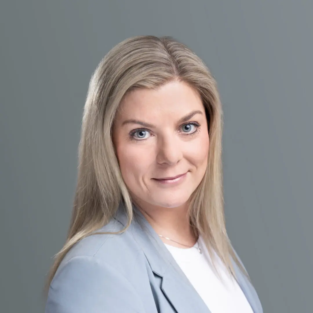 A woman with long blonde hair wearing a white shirt and jacket.