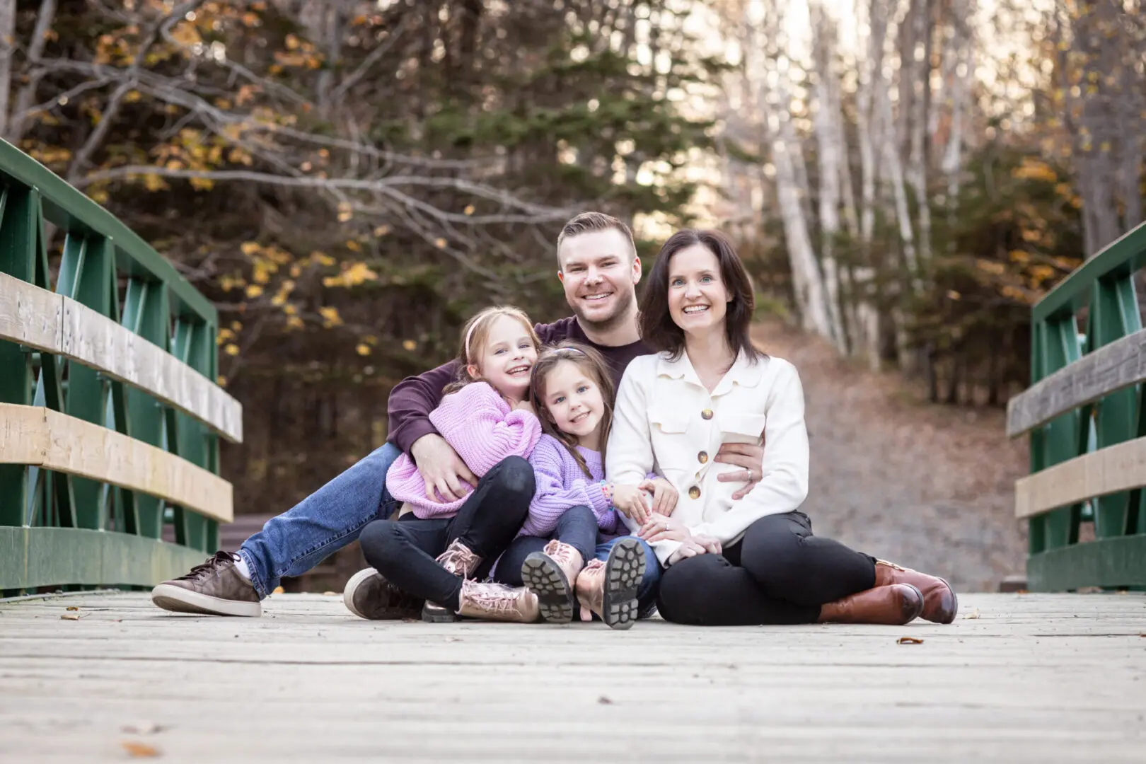 A family sitting on the ground in front of trees.