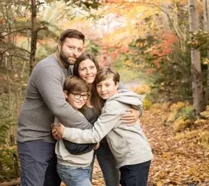 A family posing for the camera in the woods.