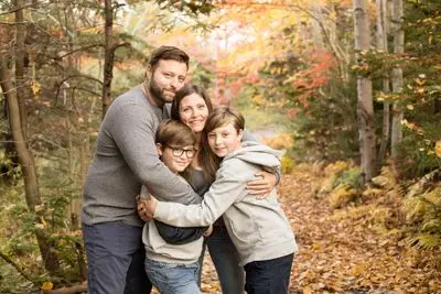 A family posing for the camera in the woods.