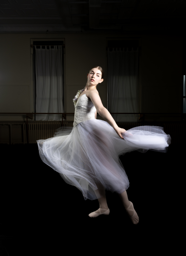 A woman in white dress dancing on the floor.