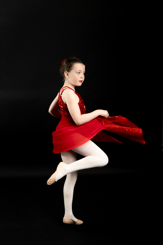 A girl in red dress and white tights jumping.